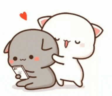 a cat runs up and hugs another cat who's using a phone